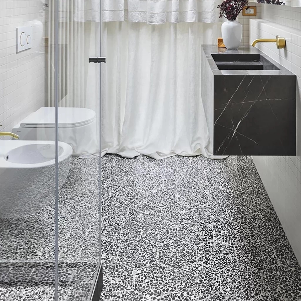 Terrazzo au motif noir et blanc au sol d'une salle de bain. 