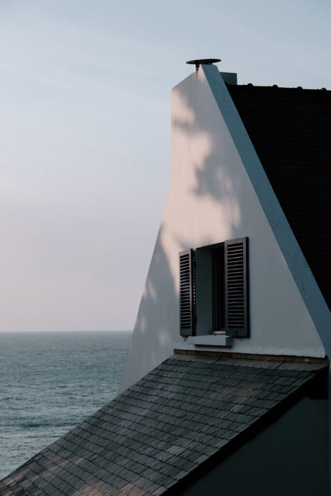 facade-de-la-maison-blanche-avec-toiture-en-ardoise-et-volets-bleus-vue-sur-la-mer